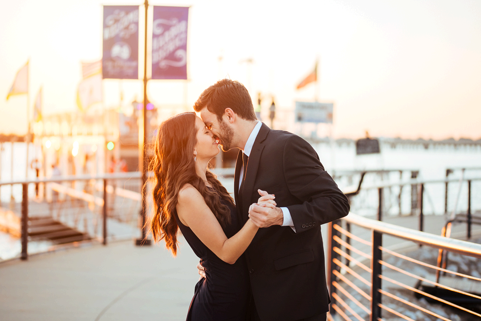 Couple kissing at the Harbor at Rockwall with sunset behind them