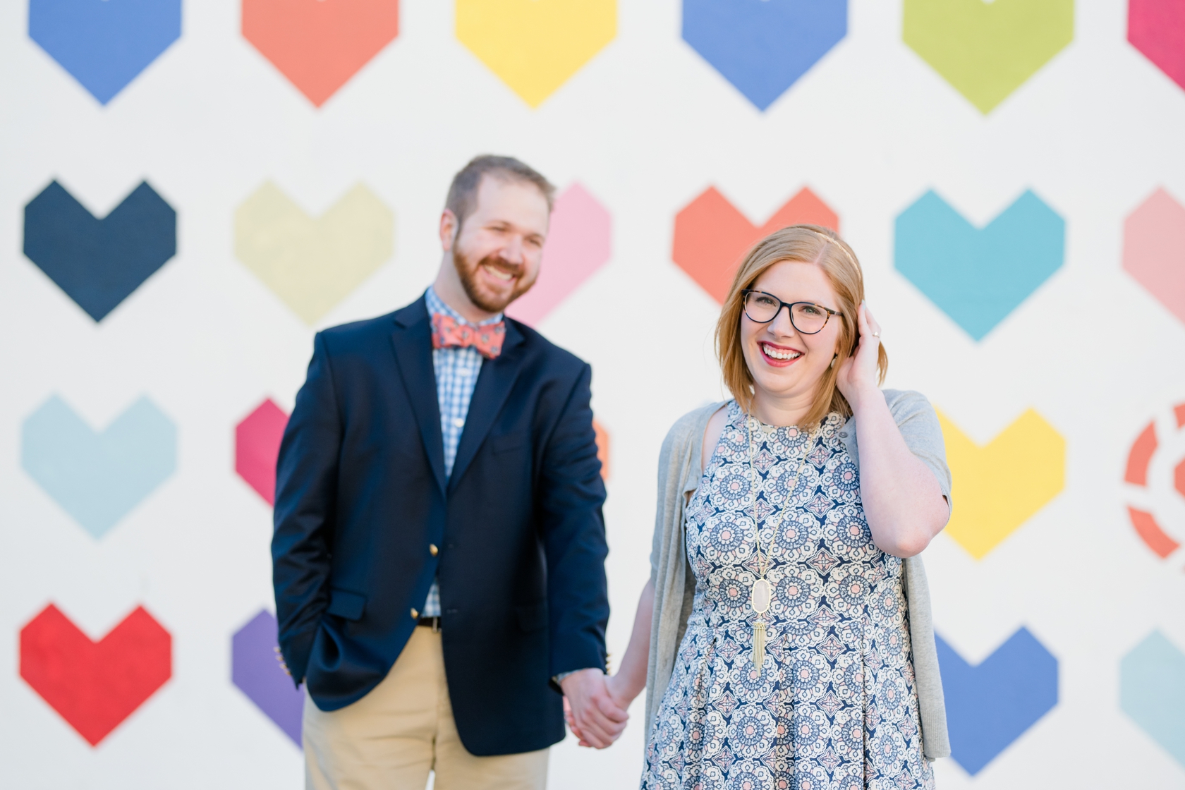 Engaged couple embracing in front of heart mural in Uptown Dallas